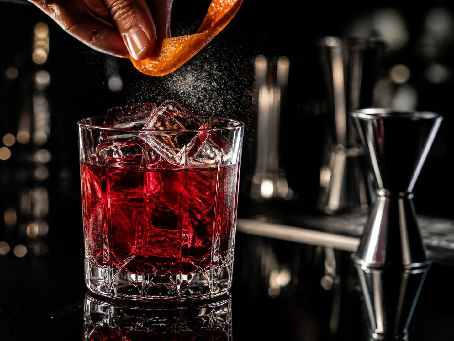 Red cocktail finished with expressed citrus oil