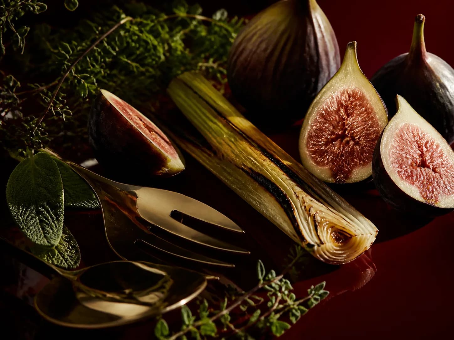 Figs, charred leek and herbs arranged as an ingredient study