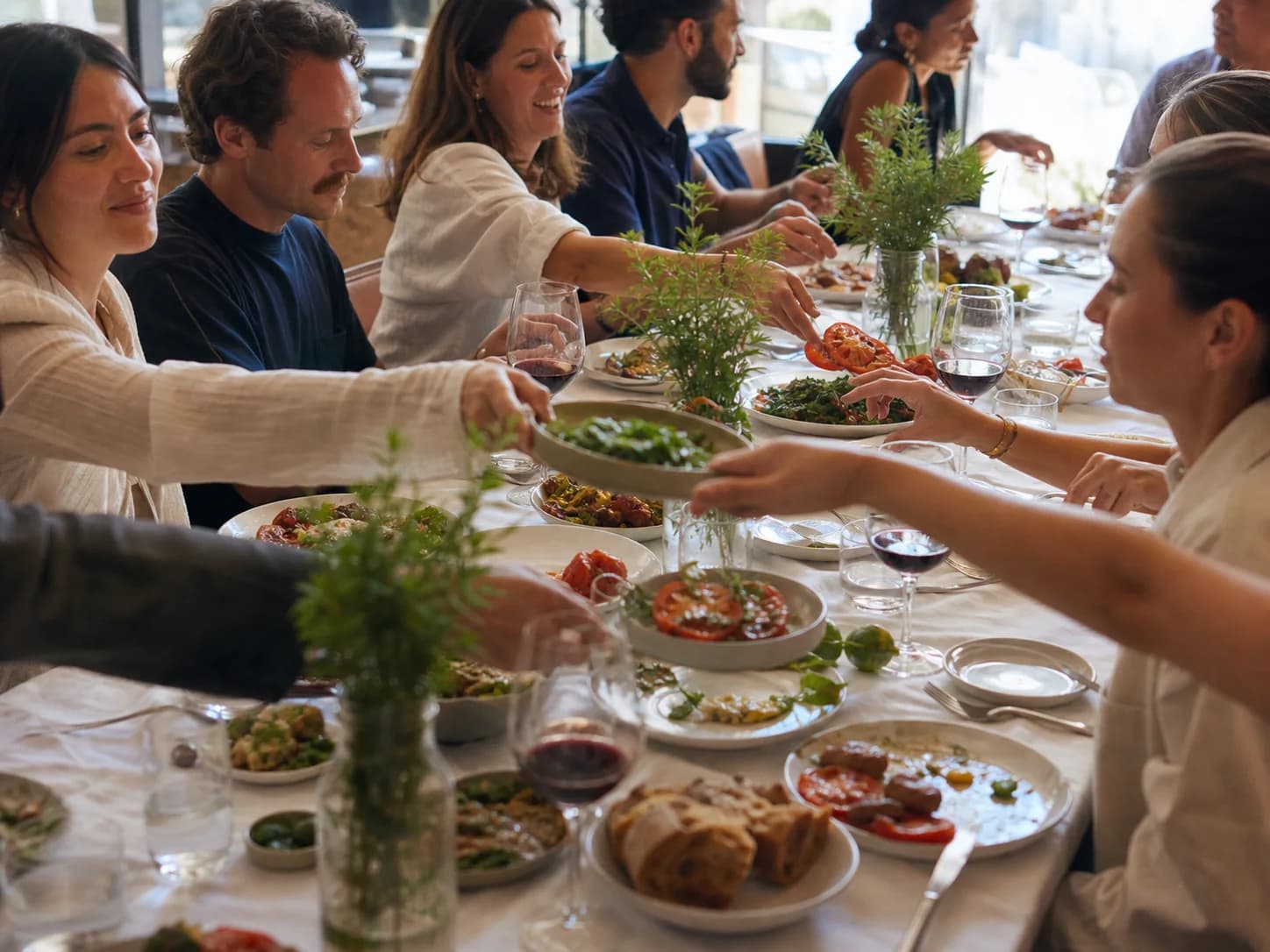 Friends sharing plates around a bright communal lunch table