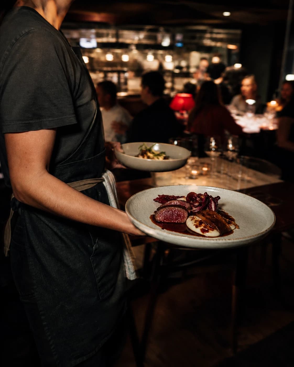 Server carrying plates through the dining room